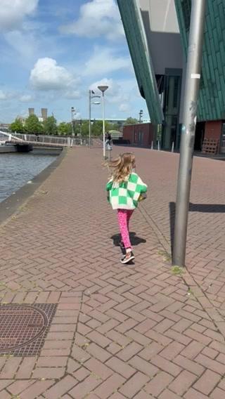 A young girl runs along a brick waterfront path on a sunny day